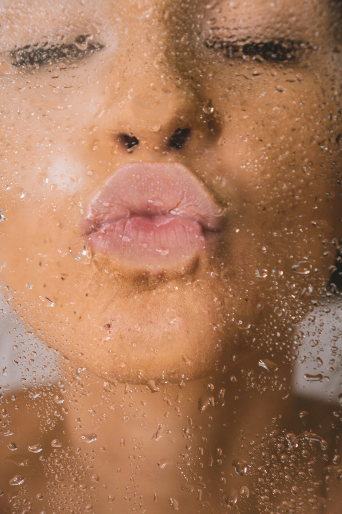 Brown woman kissing a glass window