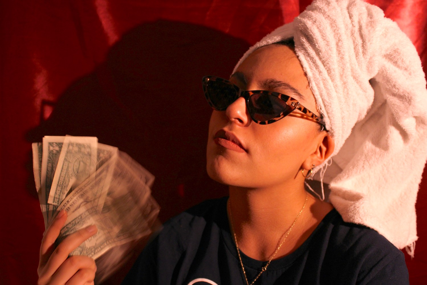 Woman with hair wrapped in towel fanning herself with dollar bills.